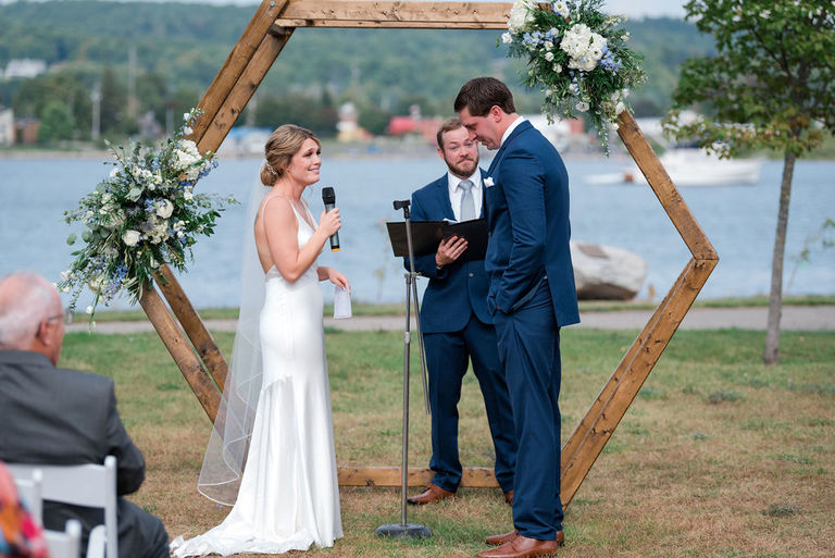 a bride gives a speech in front of Betsie Lake and an octagon arch with Victorias floral weddings