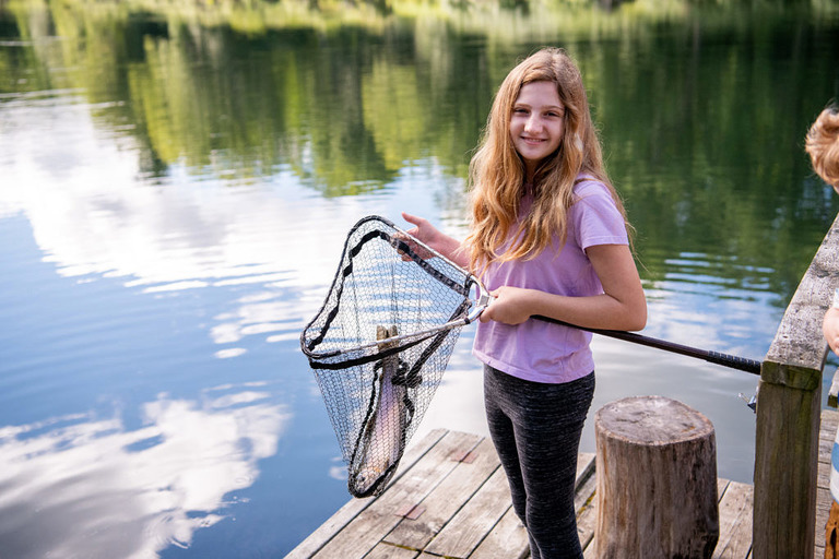 A young girl holds a fishing net with a trout in it in Mesick