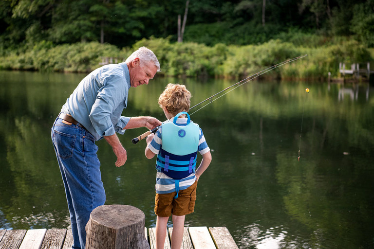 A grandfather helps a small child with his fishing pole at the waters edge in Mesick.