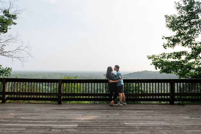 a photo of a man and woman about to kiss with her hair blowing back dramatically on the platform on the high rollaway trail for engagement pictures.