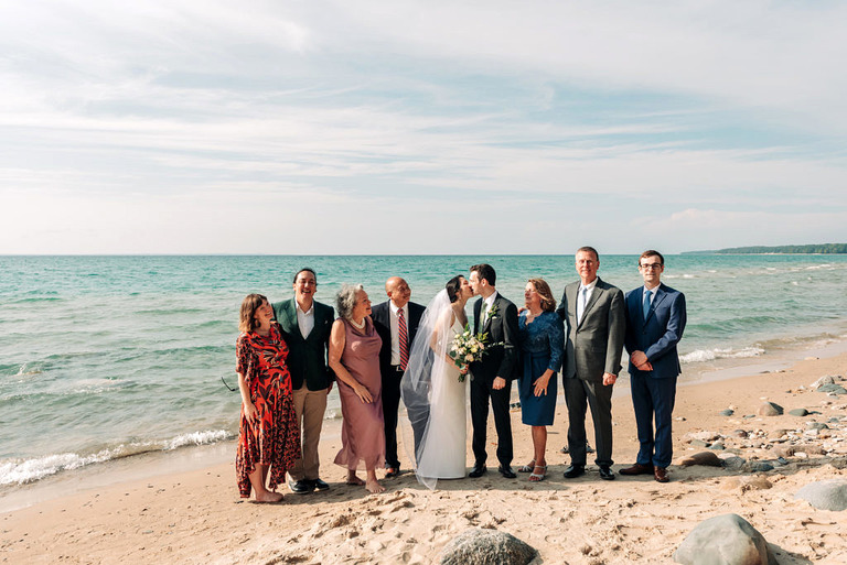 a wedding group posed on the shore of lake michigan in Kewadin.