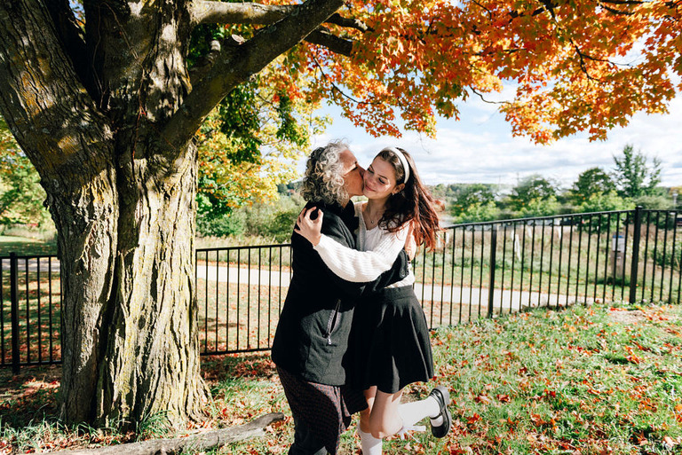 mom and daughter embrace under a fall tree in traverse city