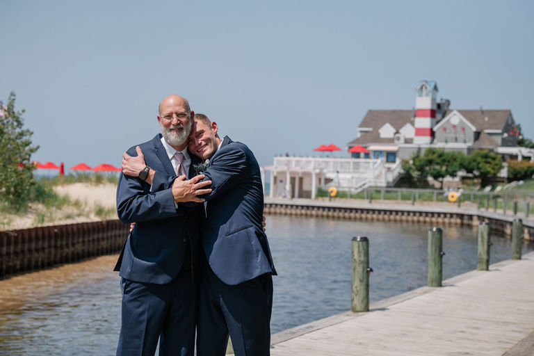 Groom gives his Dad a hug in front of the homestead.