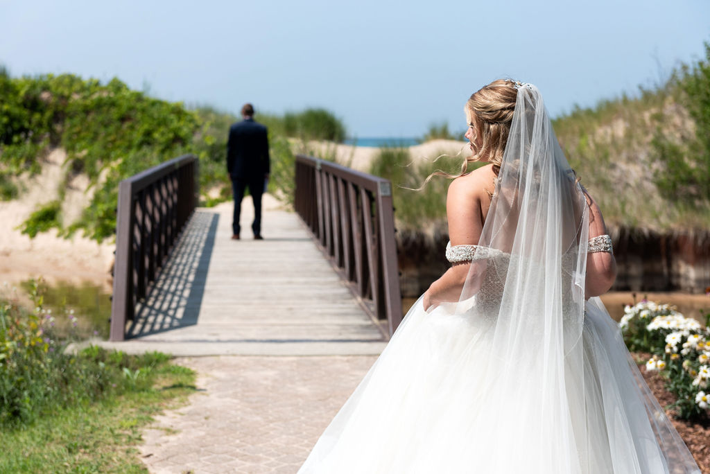 the back of a bride approaching her groom on a bridge at the Homestead resort.