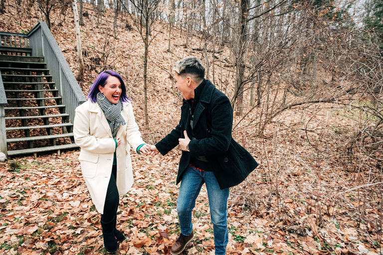 a couple runs laughing for a surprise proposal.