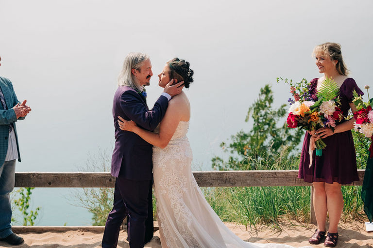 the groom romantically holds the head of his wife just before the first kiss on the Empire bluffs trail.