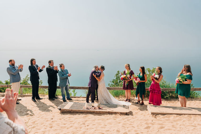 the wedding party claps for the newly married couple at Sleeping Bear Dunes.