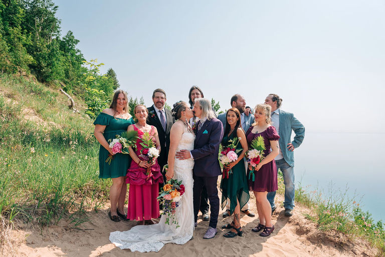 the wedding couple kisses with their party behind them at Sleeping bear dunes.