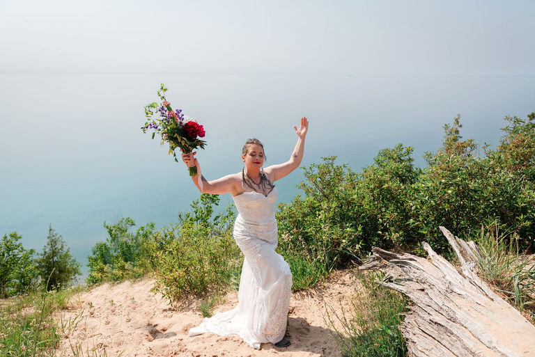 a bride poses in a goddess pose near the bluffs overlook in Sleeping Bear Dunes.