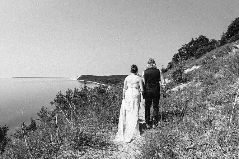 a black and white photo of the wedding couple starting down the trail at Empire Bluff in Sleeping Bear Dunes.