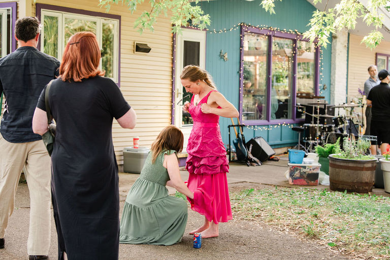 a wedding party member straightens the dress of another party member