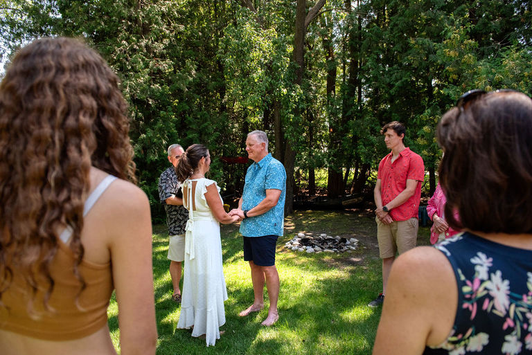 a couple exchanges vows at a micro wedding by the crystal river in Leelanau