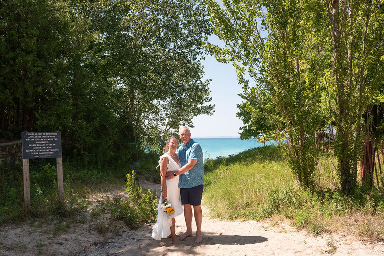 a bride and groom stand at the entrance to lake Michigan.