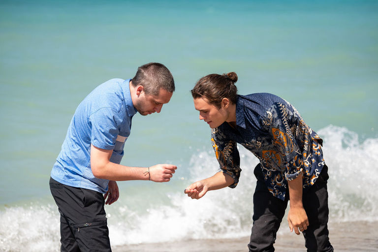 Two men look for stones on the beach at the micro wedding in Leland.