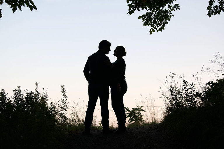 a couple stands in silhouette at the Traverse City Botanical gardens for engagement photos.