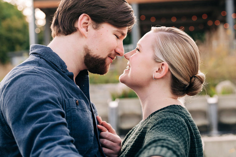 a couple stands nose to nose at the Traverse City Botanical gardens for engagement photos.