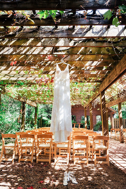The brides lace dress hanging from the pergola covered in vines at Blue Bridge.