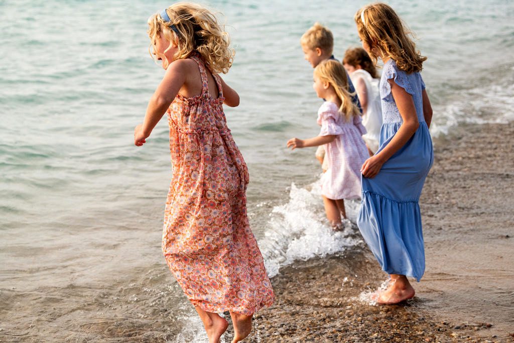 a group of children jump the waves at Van's beach for family portraits