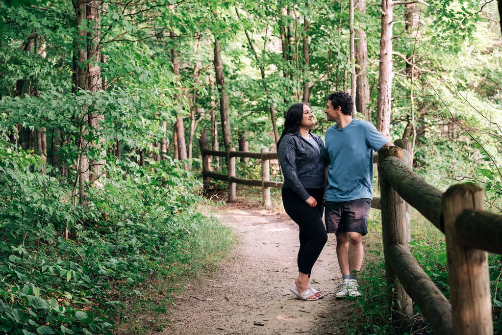 a photo of a man and woman leaning on the split rail fence on the high rollaway trail for engagement pictures.