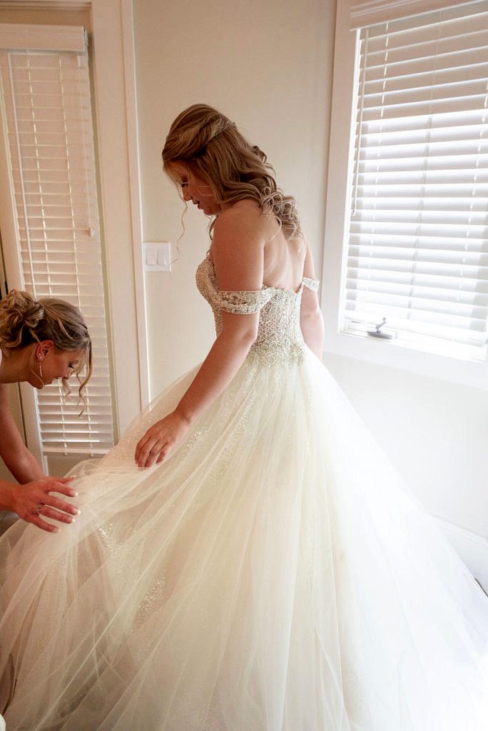 a woman is helped into her wedding dress.