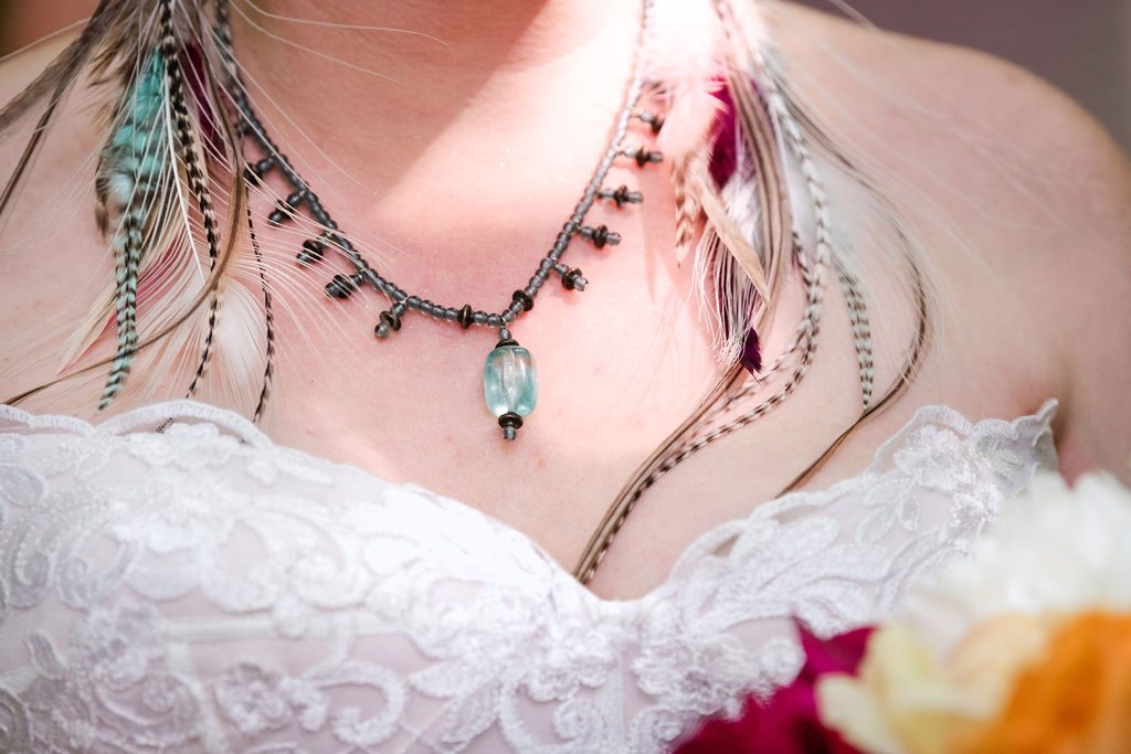 feathers and crystals adorn the neckline of the bride at the empire bluffs wedding.