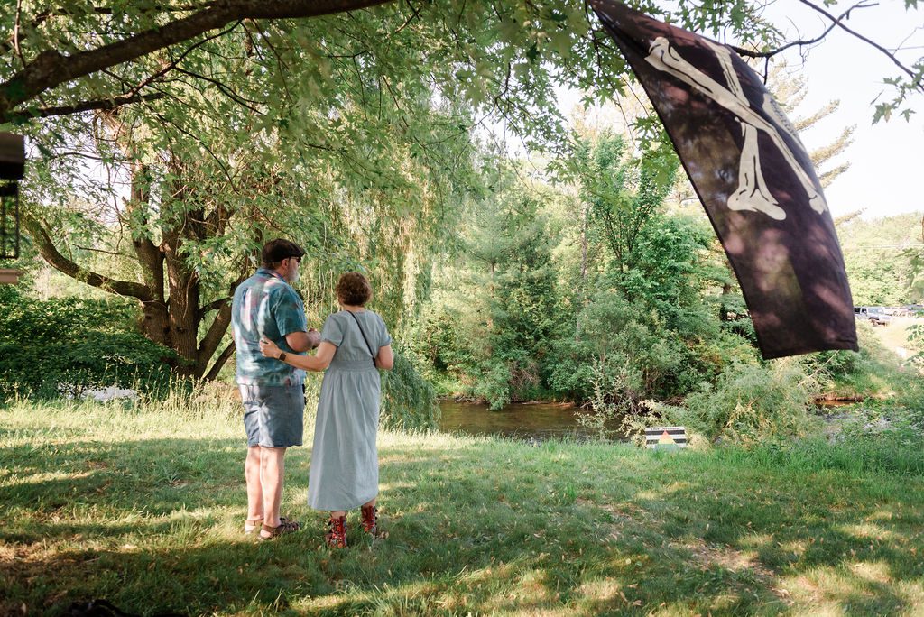 guests mingle under the willow trees next to the river