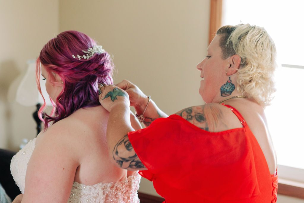 the brides mom putting her necklace on the bride at Cobblestone farm.