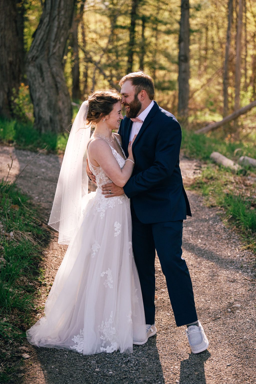 a newly married couple kisses in the sun filtered woods in Traverse City, MIchigan.